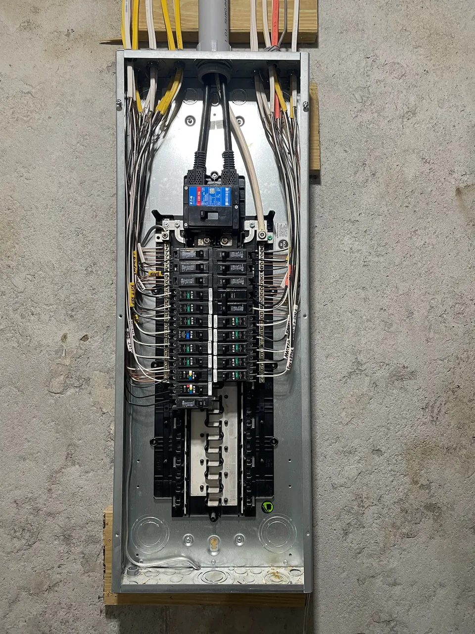 A 200 amp electrical panel with the cover open and new breakers installed and labeled.