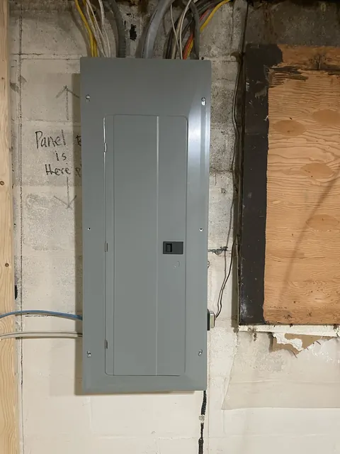 A new electrical panel with the cover closed after a replacement, mounted on an interior wall.