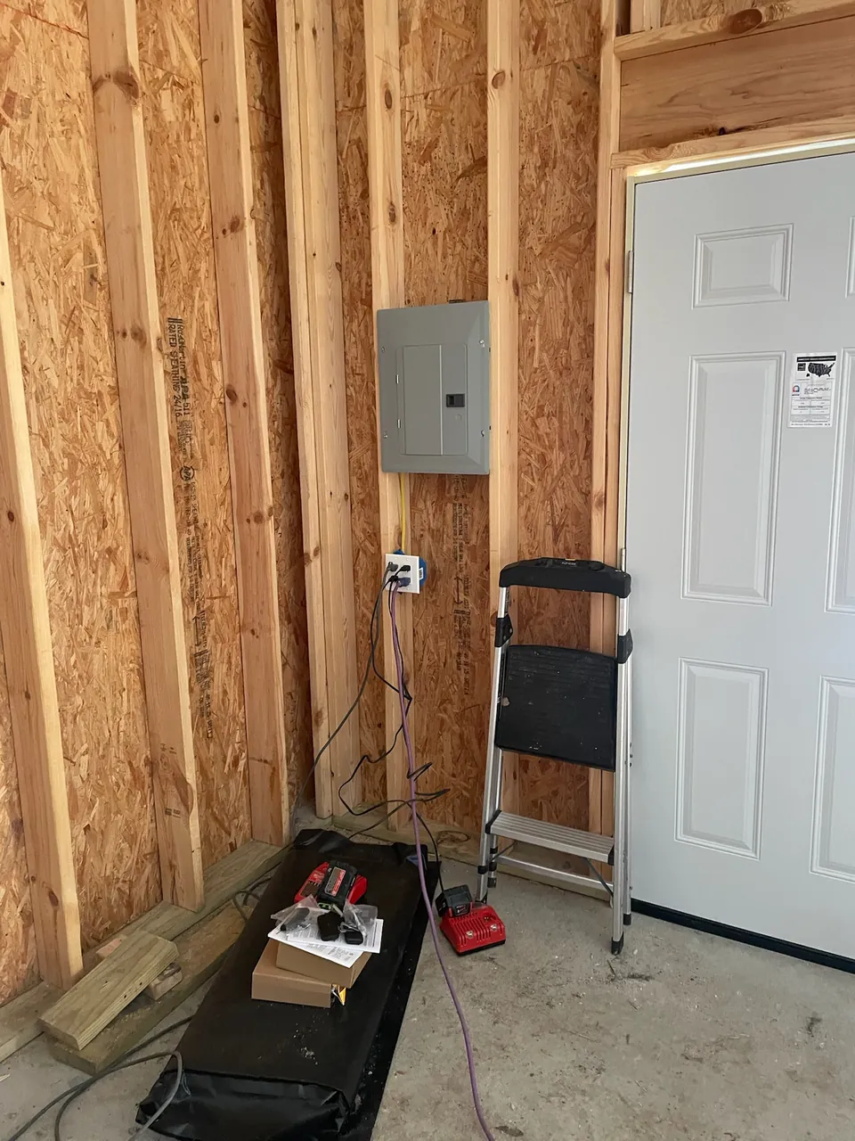 A new electrical panel installed on a garage wall with the cover on and the circuits labeled.